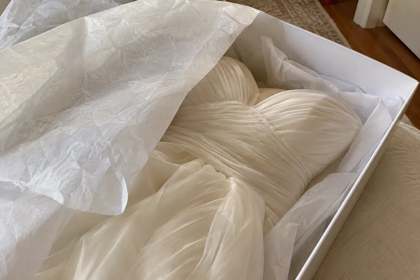 Acid-free tissue paper folded over the bodice of an ivory gown in a white box